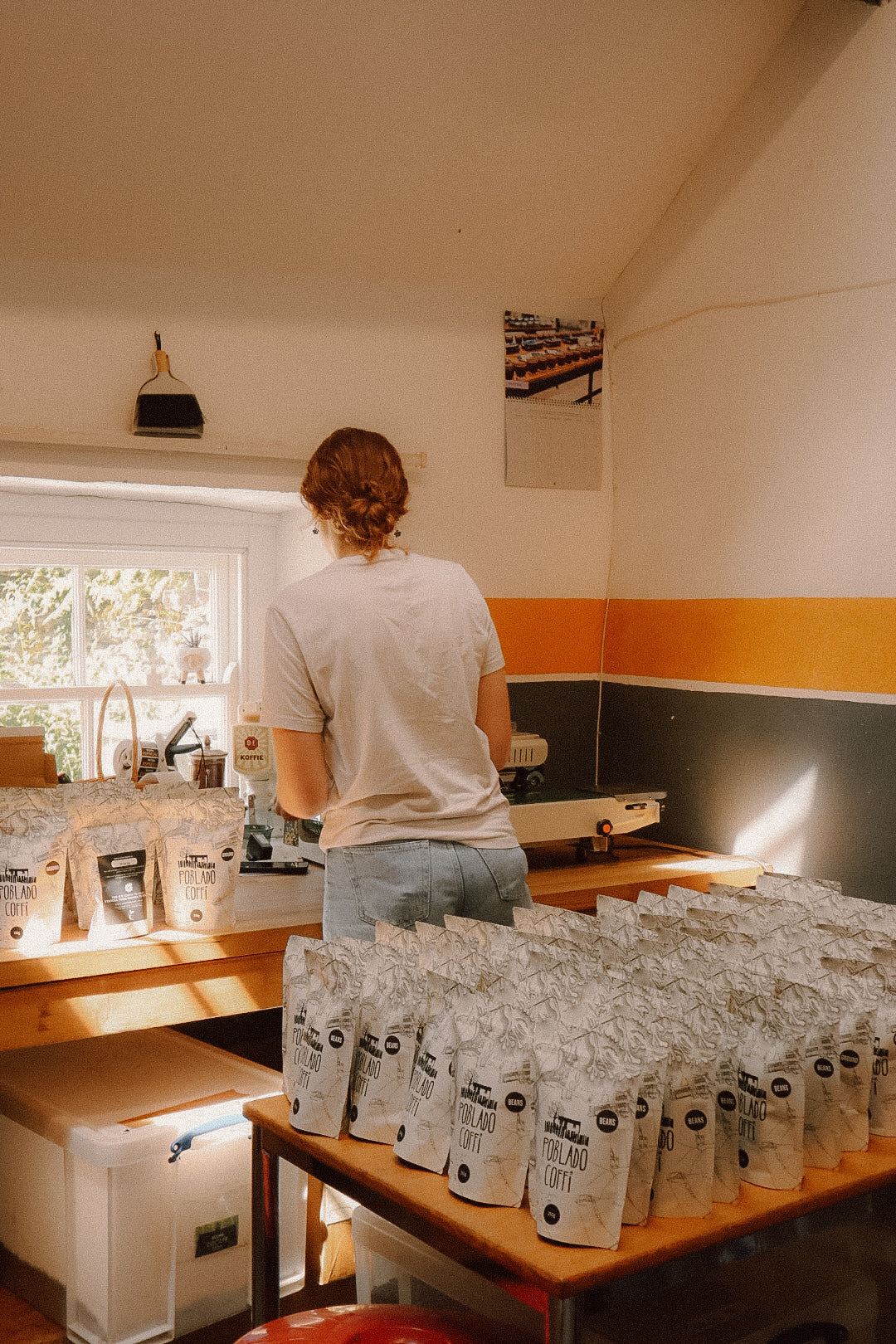 Person standing in a kitchen with coffee bags on a table